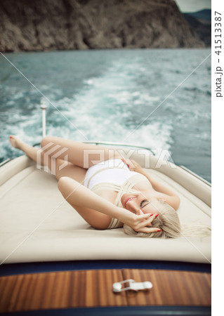 Beautiful young blonde girl is wearing white swimsuit doing summer trip on a yacht 41513387