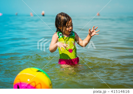 little girl gets wet after playing a ball in the sea 41514616