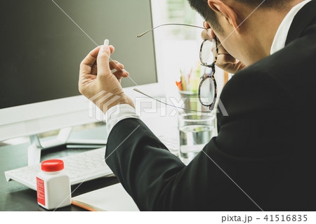 Businessman with pills in his hand at workplace Businessman with pills in his hand at workplace 41516835