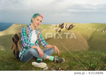 Portrait of young smiling woman traveler with multi-colored hair. Sitting high in the mountains in 41519896