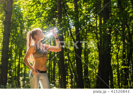 Fitness beautiful woman drinking water and sweating after exercising on summer hot day in park Fitness beautiful woman drinking water and sweating after exercising on summer hot day in park 41520843