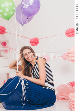 the blonde smiles and looks at the camera between the colored balls on a white background. Studio the blonde smiles and looks at the camera between the colored balls on a white background. Studio 41521419