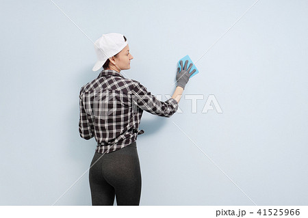Girl painter, designer and worker paints a roller and brush the wall. Smiling, working with pleasure Girl painter, designer and worker paints a roller and brush the wall. Smiling, working with pleasure 41525966