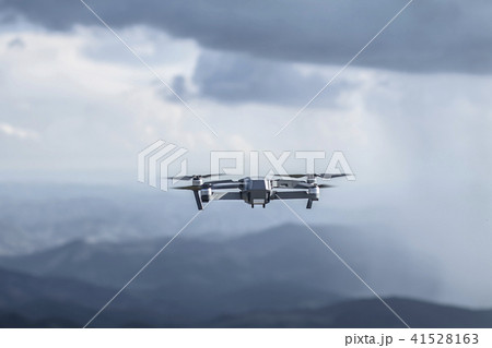 Drone quadrocopter with high resolution digital camera flying on the cloudy thunder sky 41528163