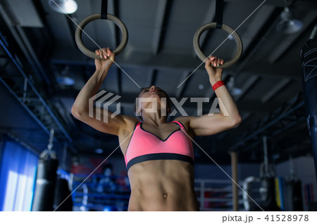 Young woman doing a pullup ongymnastic rings, in the gym 41528978