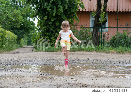 Little girl is playing in the water after rain 41531453