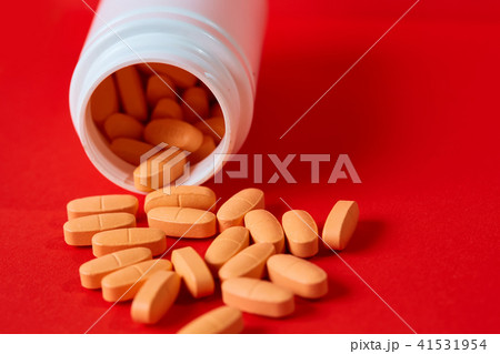 Pills spilling out of pill bottle on red. Top view with copy space.  41531954