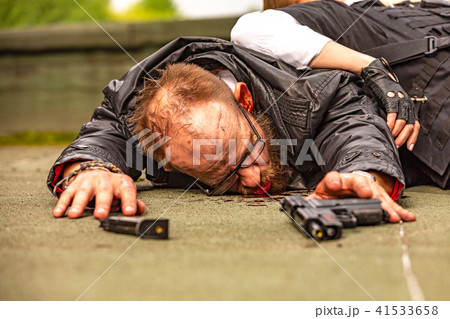 Klled woman accessorized as special agent lies on a man in blood, he pulls his hand towards the gun Klled woman accessorized as special agent lies on a man in blood, he pulls his hand towards the gun 41533658