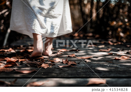 woman in white dress walking barefoot on wooden 41534828
