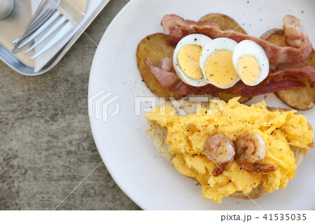 breakfast with scrambled eggs, fried potatoes bacon and shrimp breakfast with scrambled eggs, fried potatoes bacon and shrimp 41535035