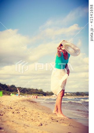Woman on beach throwing sun hat 41541698