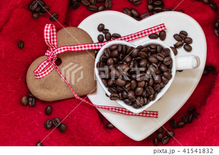 Coffee beans in heart shaped cup and dessert on red Coffee beans in heart shaped cup and dessert on red 41541832