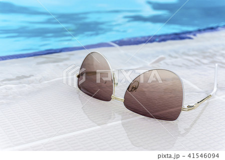 Summer sunglasses fashion concept, sunglasses on swimming edge, outdoor day light Summer sunglasses fashion concept, sunglasses on swimming edge, outdoor day light 41546094