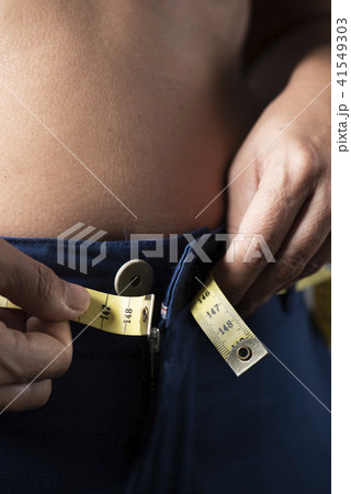 young woman trying to fasten her trousers young woman trying to fasten her trousers 41549303
