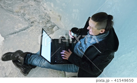 Man is sit on the internet in laptop in an ice cave. Around the mysterious beautiful ice grotto 41549650