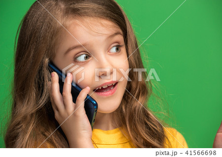 The happy teen girl standing and smiling against green background. 41566698