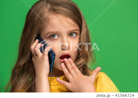 The happy teen girl standing and smiling against green background. 41566724