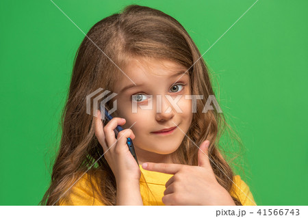 The happy teen girl standing and smiling against green background. The happy teen girl standing and smiling against green background. 41566743