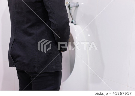 Businessman peeing to toilet bowl in restroom. Businessman peeing to toilet bowl in restroom. 41567917