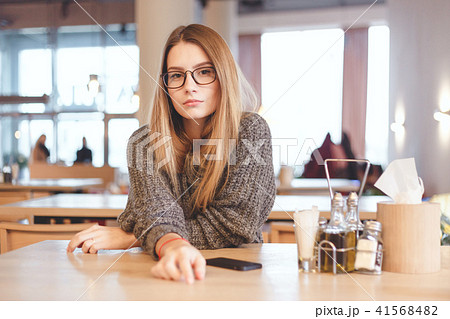 Portrait of cute freelancer girl sitting in a cafe. She wears brown hipster eyeglasses. 41568482