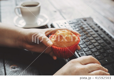 Woman eating muffin at workplace Woman eating muffin at workplace 41592503