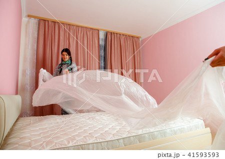 Image of young woman covering bed with polyethylene 41593593