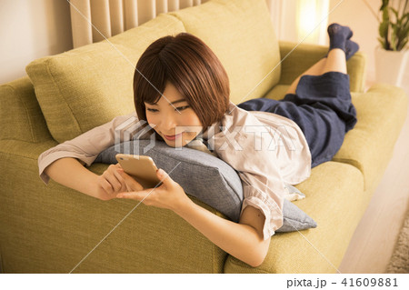 寝転んでスマホを見る若い女性 寝転んでスマホを見る若い女性 41609881