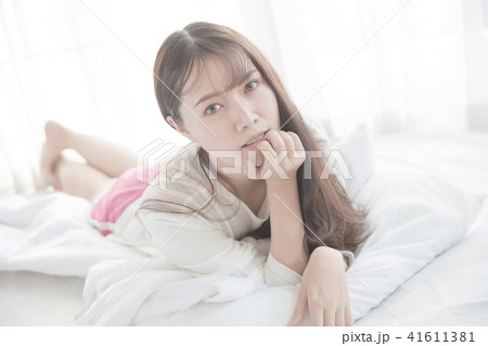 Asian young woman wake up on bed in white tone Asian young woman wake up on bed in white tone 41611381