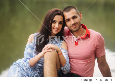 Beautiful couple walking in the park near the lake, sit on the pier Beautiful couple walking in the park near the lake, sit on the pier 41613614