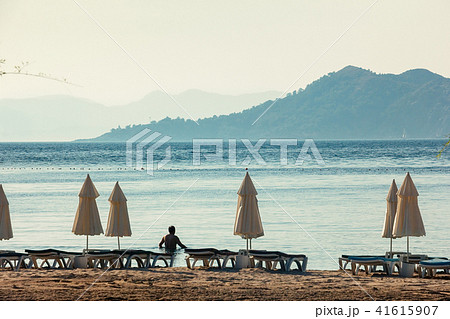 White umbrellas, blue sea big mountains on horizon White umbrellas, blue sea big mountains on horizon 41615907