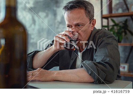 Mature man wearing dark shirt drinking cognac 41616759