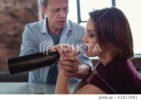 Sober husband taking bottle of wine away from drunk wife 41617091