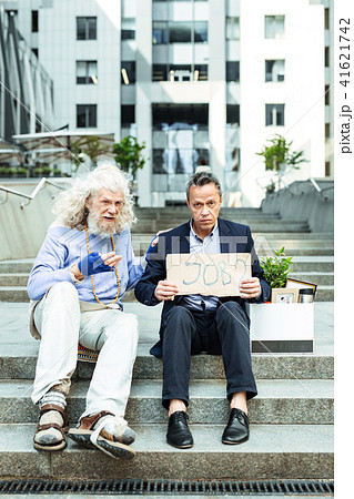 Grey-haired dismissed man sitting near case with personal belongings Grey-haired dismissed man sitting near case with personal belongings 41621742