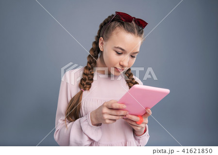 Pretty teenage girl reading social media timeline on tablet Pretty teenage girl reading social media timeline on tablet 41621850
