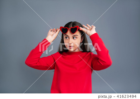 Cute teenage girl removing heart-shaped sunglasses Cute teenage girl removing heart-shaped sunglasses 41623494