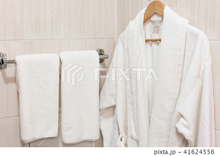 Clean white towel and bathrobe on a hanger prepared to use. Bathroom Inside rooms of a apartment or 41624556