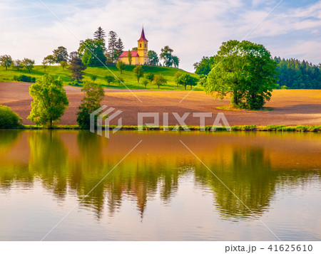 Romantic landscape with small church on the hill reflected in the pond. Sunny summer day with blue 41625610