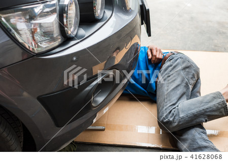 Worker are under car to change engine oil Worker are under car to change engine oil 41628068
