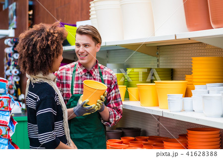 Customer buying plastic pots at the advice of a helpful worker in flower shop 41628388