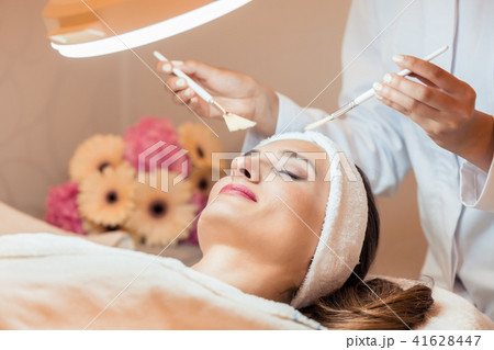 Beautiful woman during anti-aging facial massage in a modern cosmetic center Beautiful woman during anti-aging facial massage in a modern cosmetic center 41628447