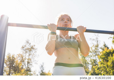Active and young woman doing pullups. 41630100