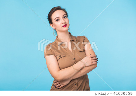 Confident young woman standing over blue background 41630359