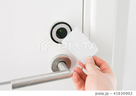 Hotel door - Young man holding a keycard in front of the electronic sensor of a room door. Concept 41630902