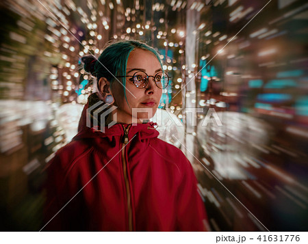 Young beautiful girl with blue dyed unusual hair, transparent glasses, piercing standing at night Young beautiful girl with blue dyed unusual hair, transparent glasses, piercing standing at night 41631776