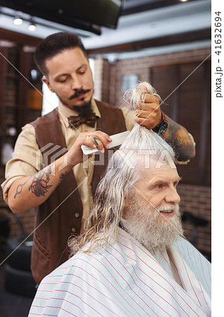 Serious bearded hairdresser serving client Serious bearded hairdresser serving client 41632694