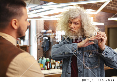 Serious bearded mature man looking at his hair 41632833