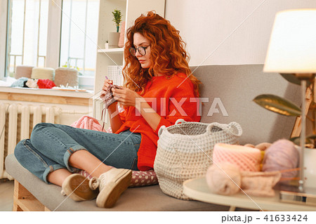 Curly haired girl sitting on grey comfortable sofa 41633424