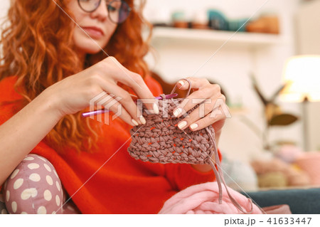 Red-haired woman with wavy hair knitting beautiful baby socks 41633447