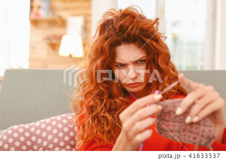 Red-haired needlewoman feeling thoughtful about chosen color 41633537