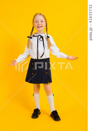 Girl with red pigtails on a yellow background. The beautiful girl put her hands to the sides and Girl with red pigtails on a yellow background. The beautiful girl put her hands to the sides and 41635732